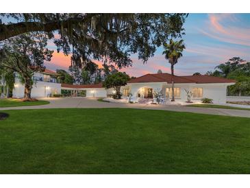 Stunning white home featuring a red tile roof, expansive lawn and circular driveway at 6381 Sw 21St Court Rd, Ocala, FL 34471