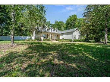 Inviting two-story home featuring a covered front porch, lush lawn, and manicured landscaping at 645 Sw 48Th Ln, Ocala, FL 34471