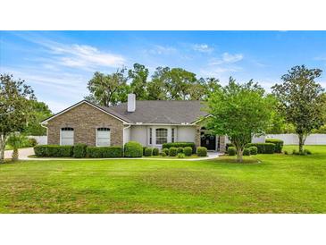 Beautiful single-story home with stone accents, mature landscaping, and lush green lawn at 1107 Se 49Th Ave, Ocala, FL 34471