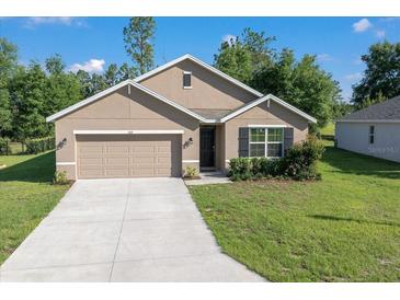 Charming single-story home featuring a well-manicured lawn, attached garage, and neutral-toned exterior at 160 Hickory Course Loop, Ocala, FL 34472