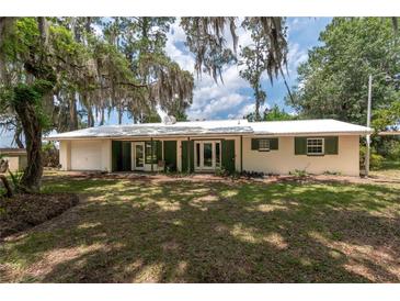 Charming single-story home with a lush lawn, bright exterior, and welcoming double doors at 23797 Ne 189Th St, Fort Mc Coy, FL 32134