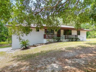 Charming single-story home with a well-maintained lawn and a inviting front porch, nestled under a shady tree at 2580 Se 157Th Lane Rd, Summerfield, FL 34491