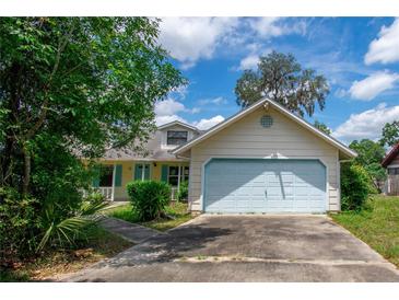 Charming single-Gathering home featuring a light yellow exterior, light blue trim and a two-car garage with a concrete driveway at 8 Juniper Pass Way, Ocala, FL 34480