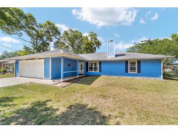 Charming single-story home features a blue exterior, attached garage, and well-kept lawn at 11 Se Fir Trail Trak, Ocala, FL 34472