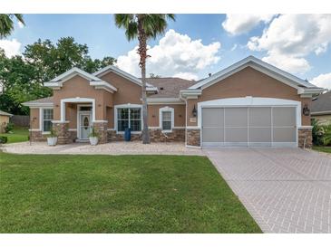 Charming single-story home with a well-manicured lawn, stone accents, a two-car garage, and a paver driveway at 12804 Se 90Th Court Rd, Summerfield, FL 34491