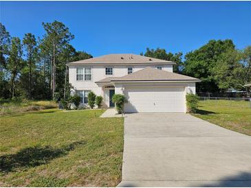 Two-story home with a well-maintained lawn and an attached two-car garage on a sunny day at 18 Fir Trail Dr, Ocala, FL 34472