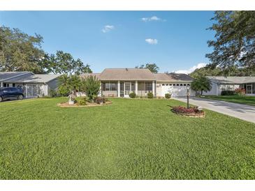 Charming single-story home with a well-manicured lawn and mature landscaping at 2208 Orkney Dr, Leesburg, FL 34788