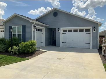 Charming single-story home with blue siding, a two-car garage, and well-maintained landscaping at 2296 Sheehan St, The Villages, FL 32163