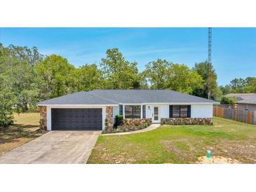 Charming single-story home with a stone facade, dark garage door, and manicured front yard at 6 Bahia Circle Loop, Ocala, FL 34472