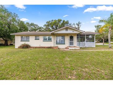 Charming single-story home with a screened-in porch and well-maintained lawn at 705 Washington Ave, Eustis, FL 32726
