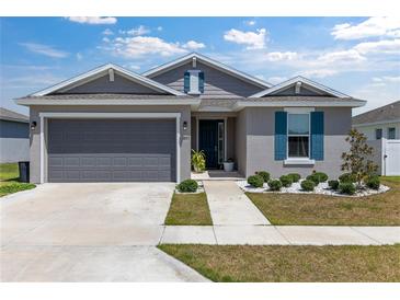 Charming single-story home with a gray exterior, blue shutters, and a well-manicured front yard at 7571 Sw 64Th Street Rd, Ocala, FL 34474