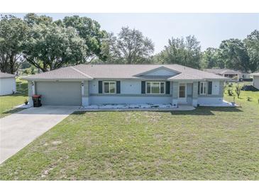 Charming single-story home features a manicured lawn and a two car garage at 10523 Sw 62Nd Terrace Rd, Ocala, FL 34476