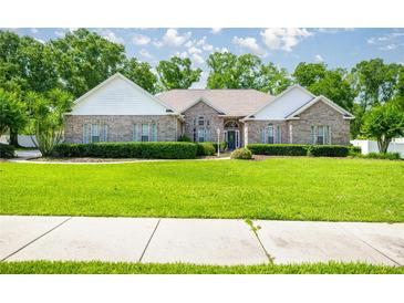 Charming brick home with a well-manicured front lawn, lush landscaping, and a welcoming entrance at 4812 Se 12Th Pl, Ocala, FL 34471