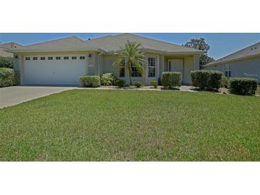 Well maintained home with a lush green lawn, a two car garage, and a small palm tree in the front yard at 9068 Se 120Th Loop, Summerfield, FL 34491