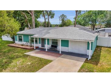 Charming single-story home with a manicured lawn, attached garage, and inviting front porch seating at 111 Almond Rd, Ocala, FL 34472