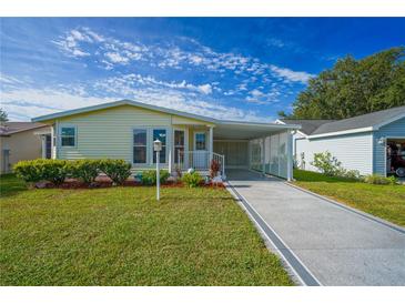 Charming single-story home with well-manicured lawn, carport and walkway under a bright blue sky at 1228 Maria Ct, Lady Lake, FL 32159