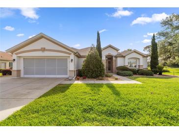 Charming single-story home featuring a well-manicured lawn and an attached two-car garage at 13015 Se 93Rd Cir, Summerfield, FL 34491