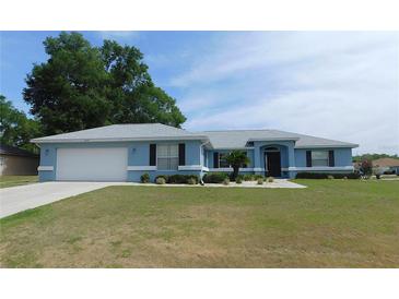 Charming light blue single-story home featuring a two-car garage, manicured lawn, and lovely landscaping at 2909 Ne 25Th St, Ocala, FL 34470
