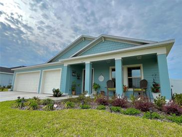 Charming blue home featuring a two-car garage, covered porch, and meticulously landscaped front yard at 5667 Sw 92Nd Pl, Ocala, FL 34476