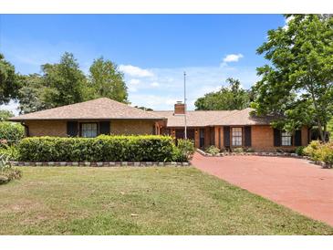 Charming brick home with a well-manicured lawn, mature trees, and a red brick driveway at 6157 Ne 25Th Ave, Ocala, FL 34479
