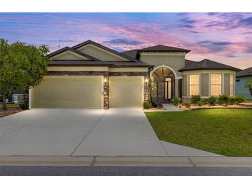 Beautiful home exterior with a two-car garage, stone accents, and well-manicured landscaping under a colorful sky at 9777 Sw 63Rd Loop, Ocala, FL 34481