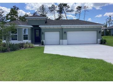 Charming single-story home with well-manicured lawn and a three-car garage on a sunny day at 10540 Sw 49Th Avenue Rd, Ocala, FL 34476
