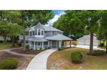 A beautiful two-story home with gray siding, porch, porte-cochere, and three-car garage at 1628 Se 29Th Ter, Ocala, FL 34471