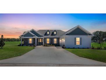 Beautiful single-story home featuring a stone facade, dormer windows, and a well-manicured front lawn at 2050 Nw 79Th Loop, Ocala, FL 34475