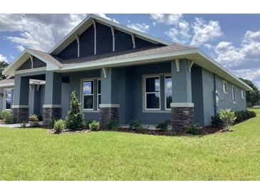Beautiful exterior of a modern home featuring manicured lawn and stylish stone accents on the columns at 8290 Nw 17Th Cir, Ocala, FL 34475