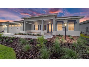 Beautiful single-story home featuring a well-manicured lawn, elegant landscaping, and a covered front entry at 8465 Sw 101St Ave, Ocala, FL 34481