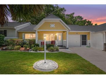 Charming yellow home featuring a well-manicured lawn and cozy front porch at 9290 Sw 89Th Ter # D, Ocala, FL 34481