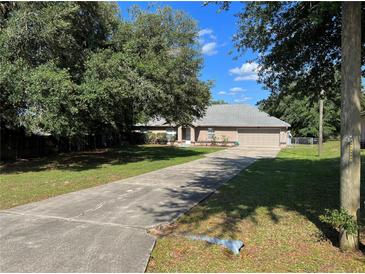 Charming home with a well-maintained lawn, mature trees, and a long driveway leading to a two-car garage at 21 Pecan Course Cir, Ocala, FL 34472