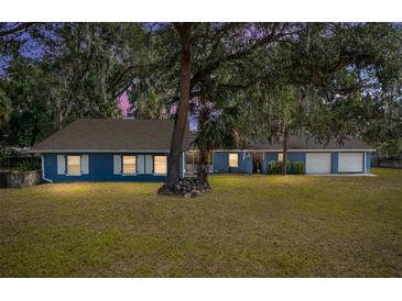 Charming blue single-story home featuring a well-manicured lawn and mature shade trees at 3823 Se 49Th St, Ocala, FL 34480