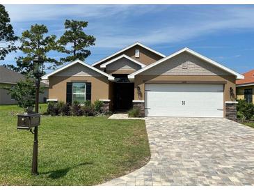 Charming single-story home with a well-manicured lawn, brick driveway, and neutral-toned exterior at 6836 Sw 179Th Court Rd, Dunnellon, FL 34432