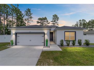 Charming single-story home boasts a manicured lawn, attached garage and modern exterior details at 7479 Sw 130Th Ln, Ocala, FL 34473