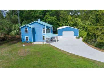 Bright blue two-story home with a metal roof, detached garage, carport, and long driveway at 12690 Ne Highway 315, Fort Mc Coy, FL 32134
