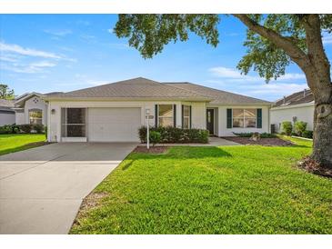 Charming single-story home with a well-maintained lawn and attached garage, under a blue sky at 1308 La Estrellita Way, The Villages, FL 32162