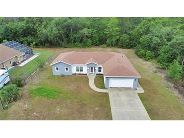 Aerial view of a single-story home with neutral gray paint, brown roof, an attached two-car garage, and a long driveway at 14550 Sw 61St Ct, Ocala, FL 34473