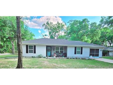 Charming single-story home with a well-manicured lawn, tidy landscaping, and a cheerful light-blue front door at 19370 Saint Benedict Dr, Dunnellon, FL 34432