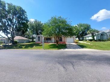 Charming single-story home with a well-manicured front yard and a paved driveway under a clear blue sky at 5110 Nw 19Th Pl, Ocala, FL 34482