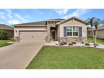 Charming home featuring a stone facade, well-manicured lawn, and a two-car garage at 6405 Sw 88Th Loop, Ocala, FL 34476