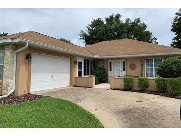 Charming single-story home featuring an attached garage, manicured landscaping, and a welcoming front entrance at 7251 Sw 115Th Pl, Ocala, FL 34476