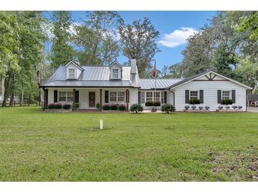 Charming single-story home featuring manicured lawn and metal roof at 12677 Se 53Rd Terrace Rd, Belleview, FL 34420