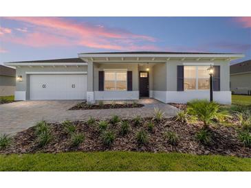 Charming single-story home featuring a well-manicured lawn, brick driveway, two car garage, and welcoming front porch at 9865 Sw 105Th Ct, Ocala, FL 34481