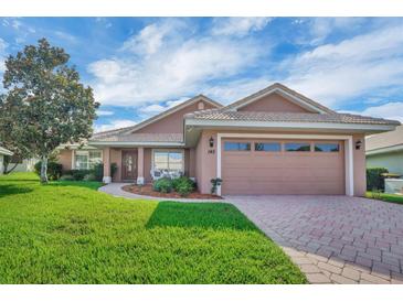 Charming single-story home with a well-manicured lawn and a two-car garage, set under a bright, partly cloudy sky at 145 Harbor Way, Auburndale, FL 33823