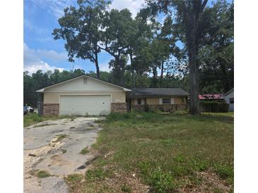 Modest single-story home with an attached garage and overgrown landscaping at 1751 Se 39Th St, Ocala, FL 34480