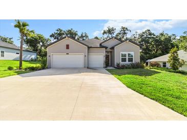 Charming home showcasing a manicured lawn, gray siding, double garage, and lush surrounding trees at 19551 Sw 77Th Loop, Dunnellon, FL 34432