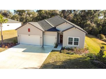 Charming home featuring a three-car garage, neutral siding and manicured lawn at 19551 Sw 77Th Loop, Dunnellon, FL 34432