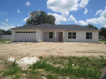 Charming single-story home featuring a crisp white exterior, a gray roof, and an attached two-car garage at 20 Pine Track Loop, Ocala, FL 34472