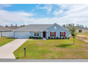 Charming single-story home with a well-manicured lawn, attached garage, and inviting red door at 3418 Sw 155Th Pl, Ocala, FL 34473